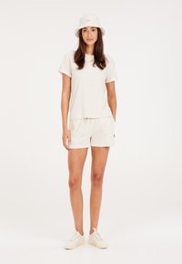 Lichtgekleurde textuur katoen t-shirt met oprol mouwen, bijpassende shorts en een bucket hat. Draagt met witte sneakers, algehele casual uitstraling.