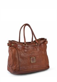Borsa tote in pelle marrone con texture liscia, due manici, dettaglio quadrato con borchie e chiusura con zip. Presenta bordi arrotondati e dettagli metallici.