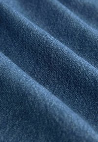 Denim-kangas tummansinisissä sävyissä, jossa on teksturoitu pinta ja vähäisiä väri- ja kudontavariaatioita. Pehmeä ja joustava materiaali.