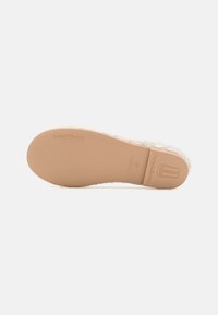 Sole di ballerine di colore chiaro con superficie testurizzata, logo impresso e finitura liscia color tan. Bordo rinforzato e design a punta arrotondata.
