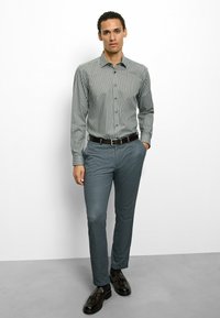Striped button-up shirt in gray and white, paired with textured blue trousers. The outfit includes a black belt and dark shoes.