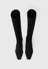Botas de ante negras hasta la rodilla con punta cuadrada y textura suave. Presentan un diseño ajustado y una construcción sin costuras, sin elementos de metal.