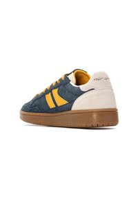 Sneakers met een marineblauwe suede bovenzijde met gele strepen, lichtgrijze suède hiel en een gumrubberen zool met een gestructureerde grip.