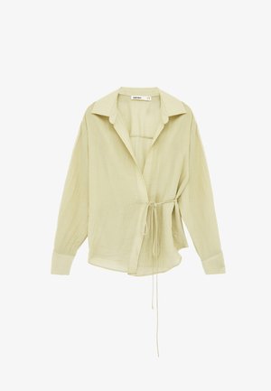 Blusa de manga larga color crema con cuello, diseño cruzado en el frente y cinturón delgado en la cintura, confeccionada en tela texturizada y ligera.