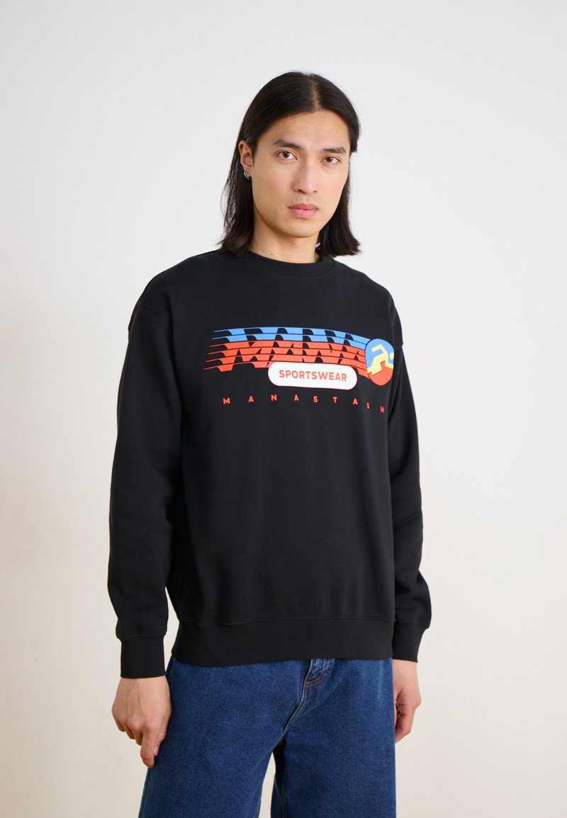 Sudadera negra con un gráfico colorido que presenta elementos en azul, rojo y amarillo. Tejido suave con puños y bajo acanalados, ajuste holgado.
