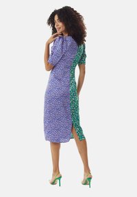 Floral-patterned, fitted dress featuring puff sleeves and a split design in blue and green. Material appears lightweight and textured.