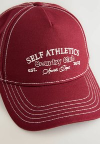 Bordo bejzbol kapa od tkanine s bijelim šavovima. Sadrži izvezeni tekst: "SELF ATHLETICS Country Club osnovan 2023."