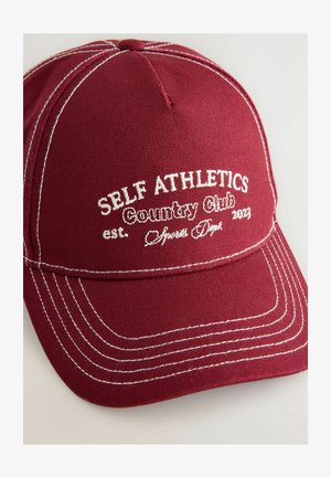 Gorra de béisbol burdeos hecha de tela con costuras blancas. Presenta texto bordado: "SELF ATHLETICS Country Club est. 2023."
