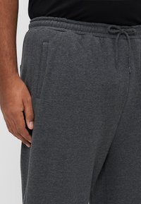 Γκρι φόρμες από μαλακό ύφασμα, με ελαστική μέση και κορδόνι, πλαϊνές τσέπες και άνετη εφαρμογή.