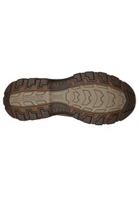 Suela de zapato de goma marrón con profundos surcos y patrones de tracción; presenta una superficie texturizada y diversas líneas curvilíneas para mejorar el agarre.