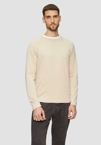Lichtbeige langarmshirt met een ronde halslijn en contrasterende witte afwerking, gemaakt van zachte stof met een subtiele textuur.