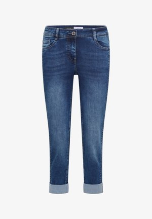 Siniset farkut, joissa käännetyt lahkeet, etunappi, vetoketjusuljenta sekä edessä ja takana taskut, esitetty yksinkertaisella valkoisella taustalla.