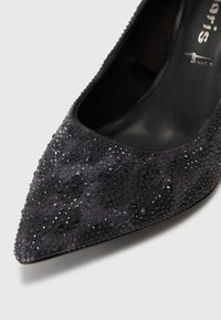 Black suede pointed-toe pump adorned with textured sparkle and gem-like embellishments on the upper. Smooth inner lining, sharp silhouette.