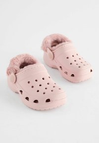 Sabots en caoutchouc rose clair avec une douce doublure en fourrure, dotés de trous de ventilation et d'une sangle arrière pour un maintien sécurisé. Bout rond et semelle texturée.