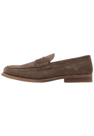 Brun ruskinds loafers med rund tå, flad hæl og en dekorativ rem over toppen. Glat tekstur med enkle syninger.