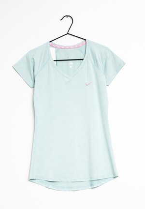 Lyseblå kortærmet V-hals Nike-shirt med et lille pink swoosh-logo på venstre bryst, hængt på en sort bøjle på hvid baggrund.