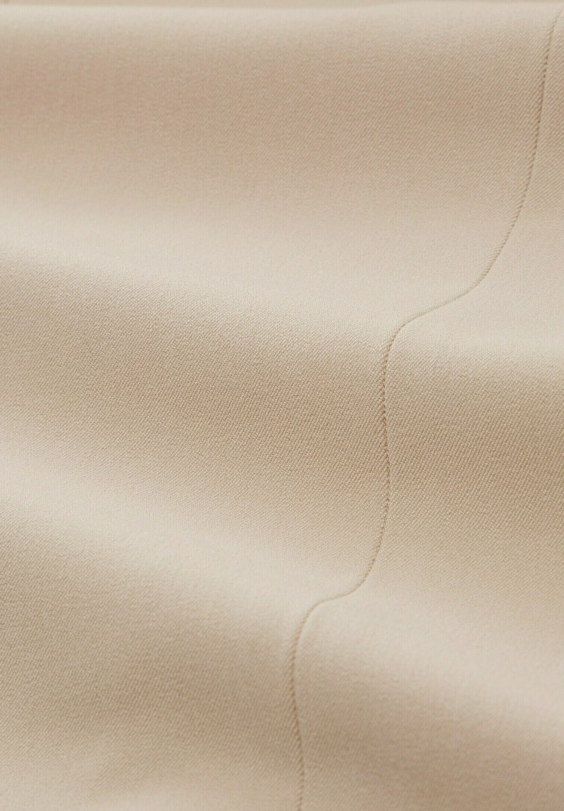 Tessuto beige con una texture liscia, caratterizzato da sottili linee diagonali. Il materiale appare morbido e leggermente lucido.
