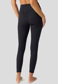 Svarta leggings med hög midja, tight passform och mjukt material, med minimala sömmar och ankellängd.