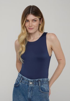 Body blu navy senza maniche con scollatura rotonda, abbinato a pantaloncini di jeans azzurri a vita alta con una cintura elastica.