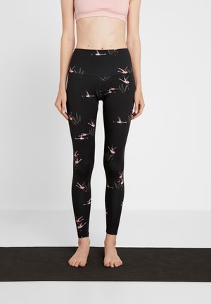 Leggings neri con un motivo floreale che presenta fenicotteri rosa e foglie verdi, realizzati in materiale elastico con una vita alta.