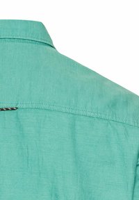 Lichtturquoise shirt met een button-down kraag. Gemaakt van een zachte stof met een subtiele textuur en contrasterende stikdetails.