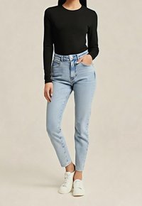 Musta pitkähiha-yläosa yhdistetty vaaleansinisiin korkeavyötäröisiin farkkuihin. Farkuissa on suoralahkeinen malli. Malli käyttää valkoisia tennareita.