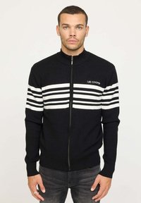 Veste zippée noire avec un col montant, ornée de rayures horizontales blanches et du logo "LEE COOPER" sur le devant. Texture tricotée.
