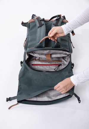 Zaino con un'esterno verde, dettagli beige e un compartimento con cerniera. L'interno presenta un tessuto a scacchi grigi e tasche per l'organizzazione.