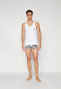 White cotton tank top paired with patterned black and white swim shorts featuring a smooth texture and a fitted design.