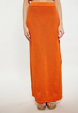 Oranje maxi rok met een gebreid patroon, voorzien van een aansluitende tailleband en zijsplitsen. Gepaarde met chunky platform sandalen.