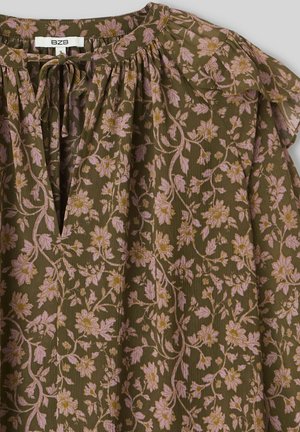 Blouse à imprimé floral en vert olive avec des fleurs roses et des accents dorés, présentant un col froncé et des manches à volants. Tissu texturé.