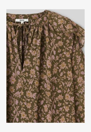 Blouse à imprimé floral en vert olive avec des fleurs roses et des accents dorés, présentant un col froncé et des manches à volants. Tissu texturé.