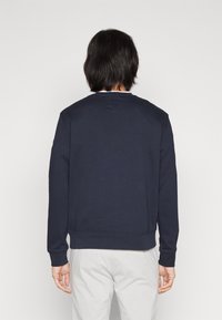 Felpa blu navy con maniche lunghe, girocollo e polsini e orlo a coste. Tessuto di cotone morbido, design minimalista, senza loghi visibili.