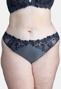 Schwarze Spitze und Netz-Bikiniunterhosen mit einem Blumenmuster entlang des Taillenbundes, einem glatten, undurchsichtigen grauen Körper und gewellten Kanten.