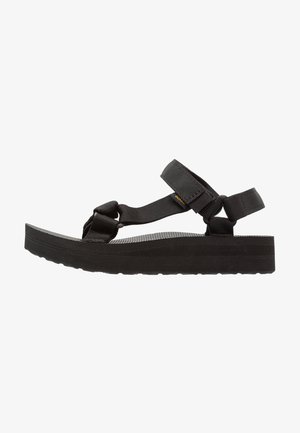 Black sandals featuring adjustable nylon straps, a chunky rubber sole, and textured footbed for enhanced grip. Lightweight, open design.