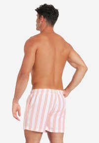 Badehosen für Herren mit pink-weißen vertikalen Streifen, elastischem Bund und seitlichen Taschen. Das Material hat eine glatte, leichte Textur.