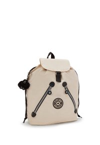 Zaino in nylon beige con chiusura a pattina, cerniere nere e un'etichetta rotonda. Presenta un portachiavi con una scimmia peluche e spallacci regolabili.