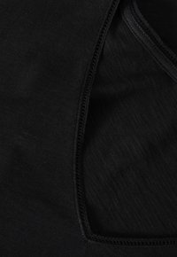 Tessuto nero con una texture liscia, caratterizzato da un colletto arrotondato e dettagli di cucitura visibili lungo i bordi.