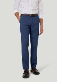 Blaue gemusterte Hose aus Stoff mit strukturiertem Finish, getragen mit einem weißen Hemd mit Knöpfen und einem braunen Ledergürtel. Braune Schuhe runden den Look ab.