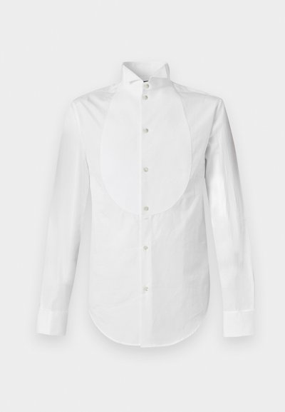 Λευκό μακρυμάνικο πουκάμισο με γιακά σε σχήμα φτερού και στρογγυλεμένη εμπρόσθια λωρίδα, κουμπωμένο στο κέντρο.