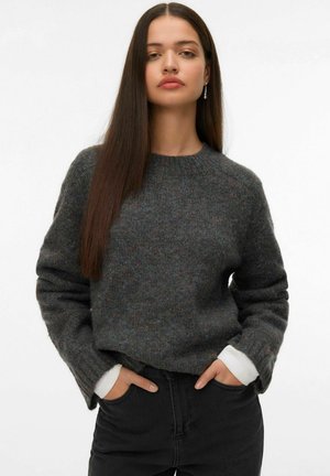Pull en tricot gris avec un col rond, des poignets côtelés et des accents blancs aux manches, présentant un tissu texturé et chaleureux.