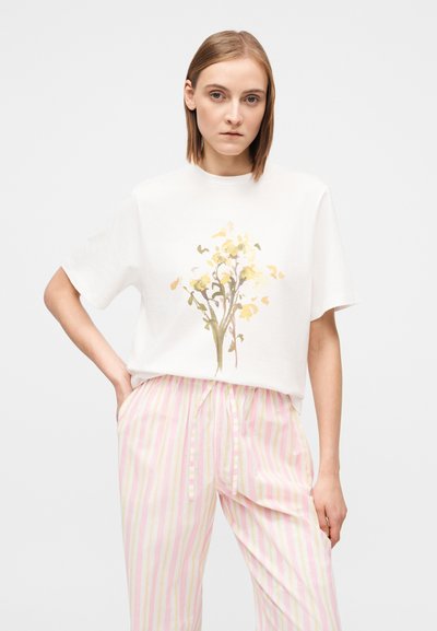Λευκό κοντομάνικο μπλουζάκι με λουλουδάτο σχέδιο σε απαλό κίτρινο και πράσινο. Συνδυασμένο με ροζ ανοιχτό και λευκό ριγέ παντελόνι πυτζάμας.
