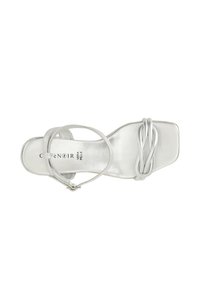 Sandal in pelle argento con punta quadrata, sottili cinturini alla caviglia e un dettaglio frontale attorcigliato. Texture liscia con una finitura lucida.