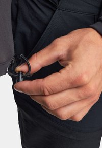 Czarna kurtka o gładkiej fakturze, z ręką dostosowującą zapięcie na suwak, prezentująca funkcjonalny design odzieży oraz zapewniającą pewne dopasowanie.