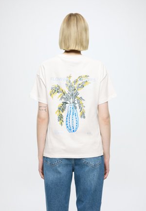 Μπεζ βαμβακερό t-shirt με στάμπα ενός μπλε βάζου με κίτρινο και πράσινο ανθικό σχέδιο στην πλάτη. Άνετη γραμμή και κοντά μανίκια.