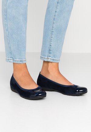 Marineblå balletflade med en patentlæder tåkap og en overdel i ruskind. Skoene har en lav, fleksibel gummisål.