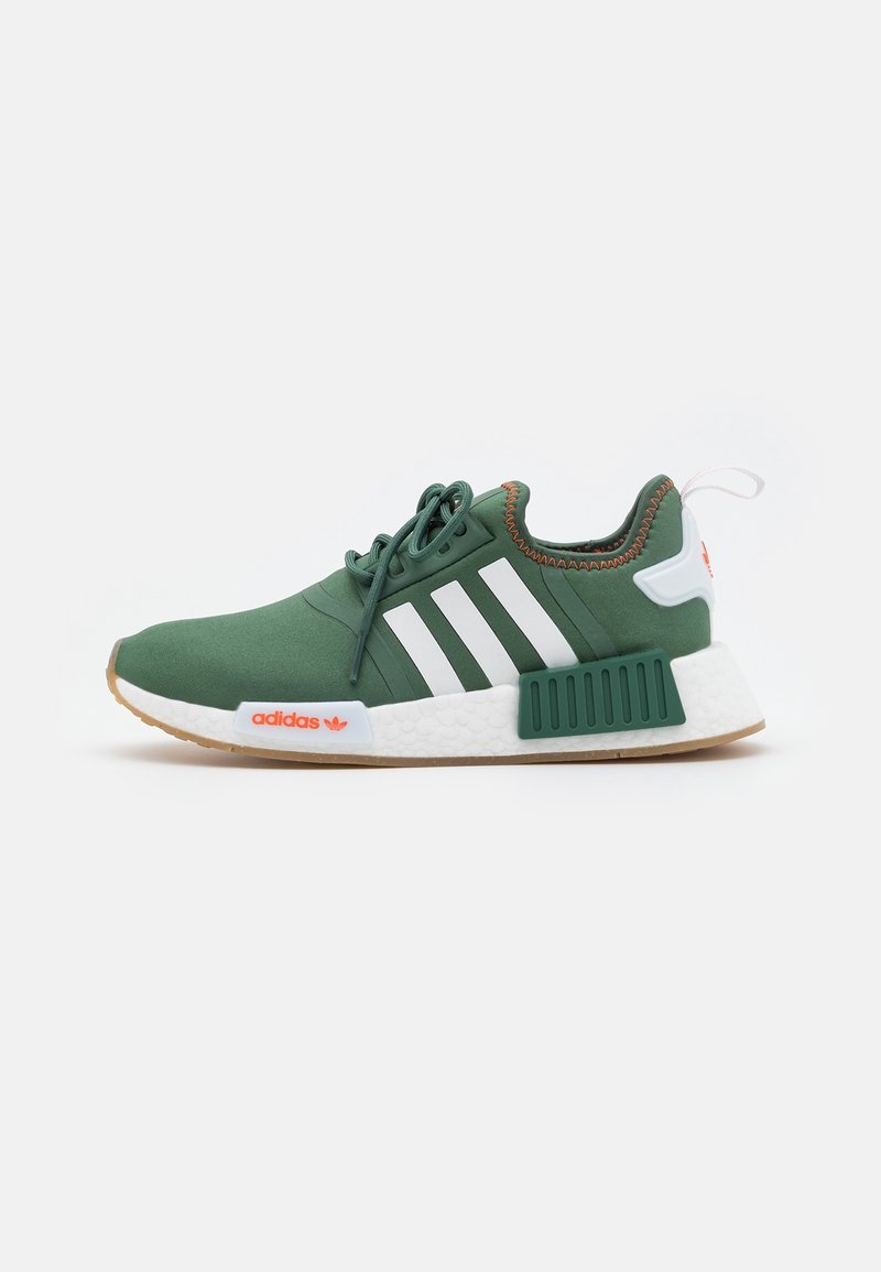 Green athletic shoes with white stripes, textured upper, gum outsole, and orange accents. Features a padded collar and lace closure.