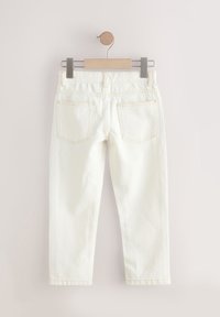 Weiße Jeans mit geradem Bein, die auf einem Holz- und Metallbügel hängen, von hinten gezeigt mit sichtbaren Taschen und Gürtelschlaufen.