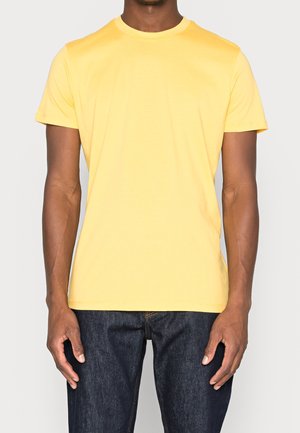 T-shirt di cotone gialla con scollo rotondo e maniche corte, esposta su uno sfondo neutro. Design minimalista senza pattern visibili.