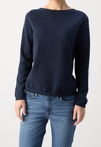 Maglione navy blu a maniche lunghe in morbido tessuto a maglia, collo rotondo, vestibilità comoda, abbinato a jeans in denim azzurro. Design minimalista.